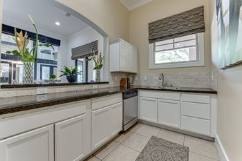 A kitchen with white cabinets and a black countertop.